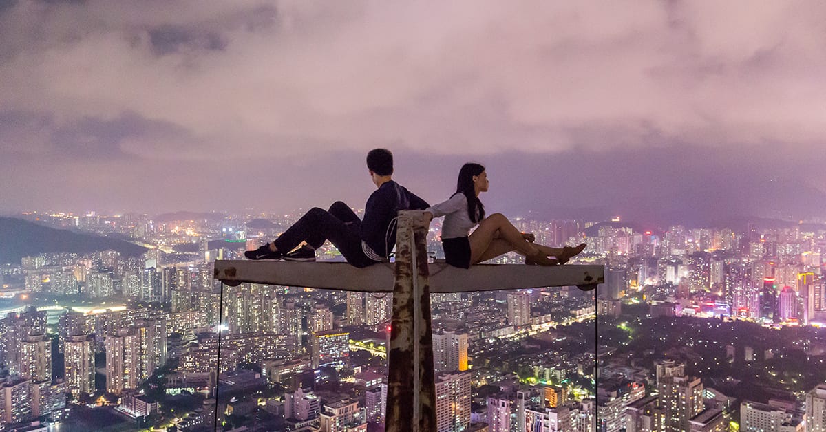 Two people on a tower overlooking a city.