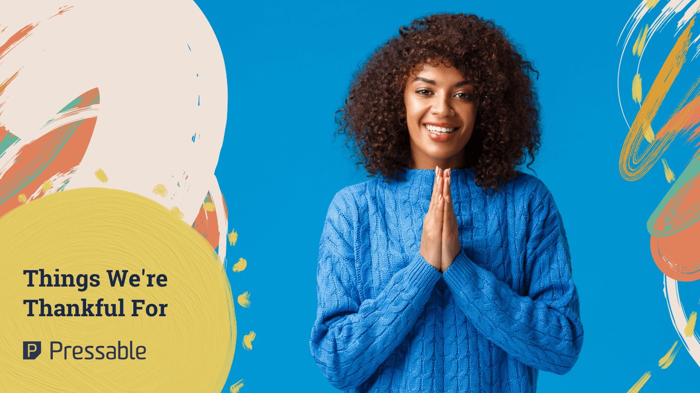 Woman of color with natural hair wearing blue sweater smiling in thankful hand gesture